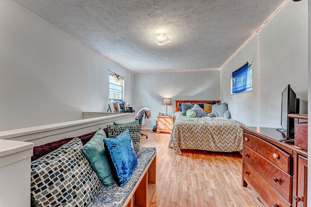 A bedroom with a bed, dresser, and couch.