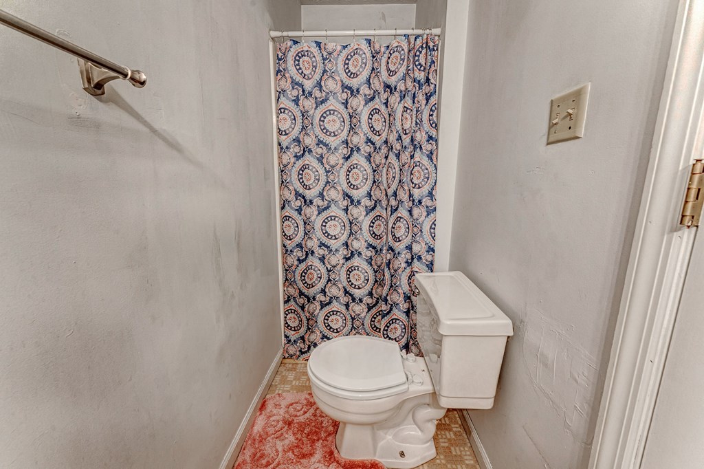 A white toilet in a bathroom with a blue and white shower curtain.