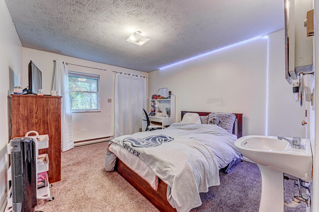A bedroom with a bed, a television, and a window with curtains.