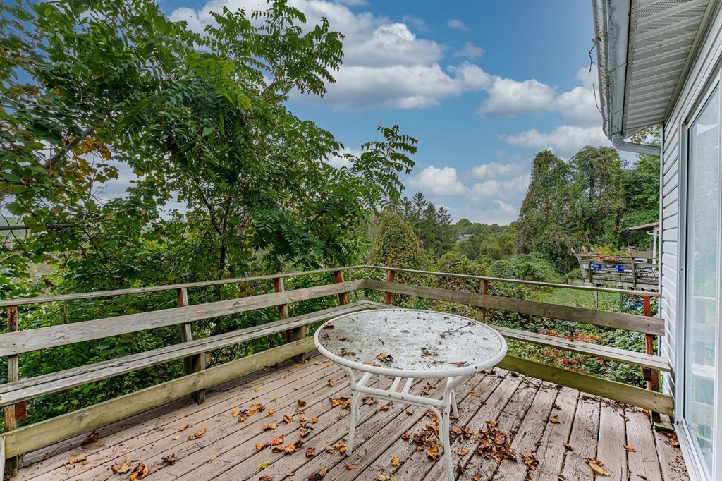 A wooden deck with a table and chairs overlooking a lush green forest.