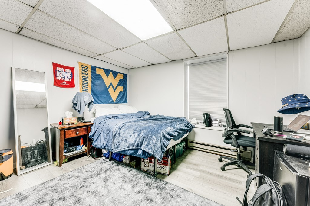 A bedroom with a bed, desk, chair, and a WV banner on the wall.