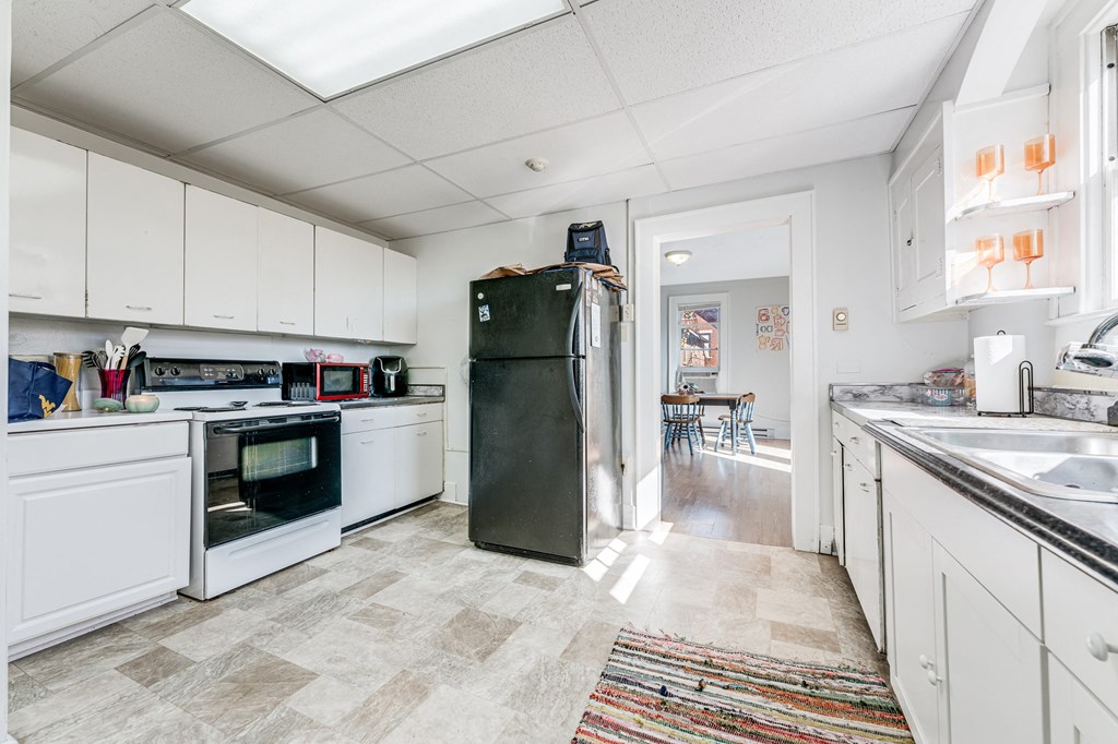 A kitchen with a black fridge and white cabinets.