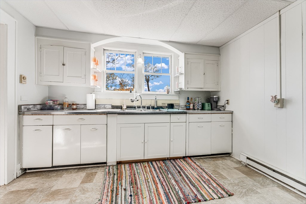 A kitchen with white cabinets and a window with a view of trees.