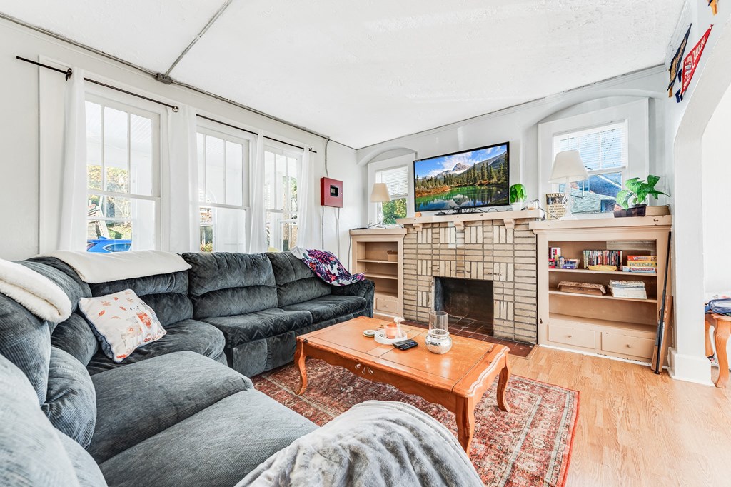 A living room with a grey couch, a fireplace, and a television on the wall.
