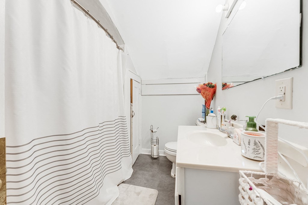 A white bathroom with a white sink and a white toilet.