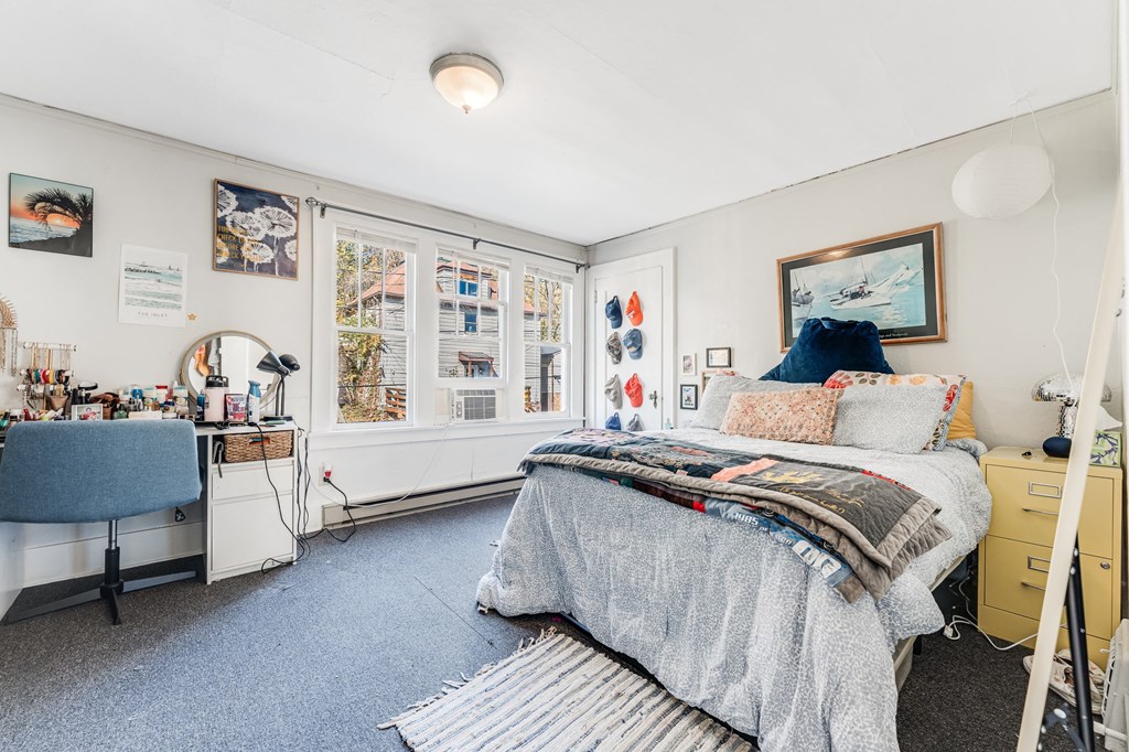 A bedroom with a bed, a desk, and a window with a view of the city.