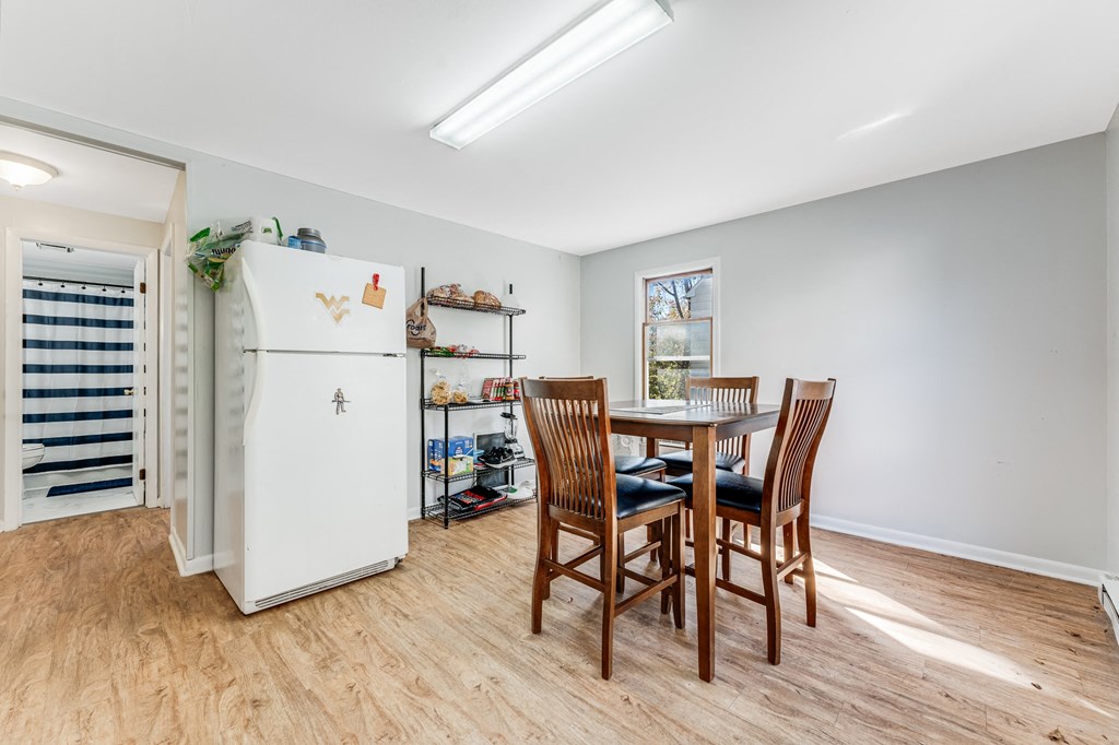 A white refrigerator is in a kitchen with a table and chairs.