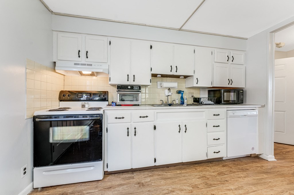 A kitchen with white cabinets and appliances.