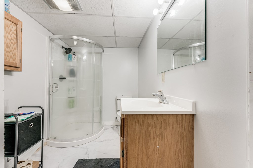 A bathroom with a sink, mirror, and shower.