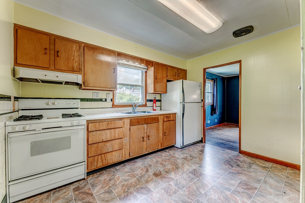 A kitchen with wooden cabinets and a white stove top oven.