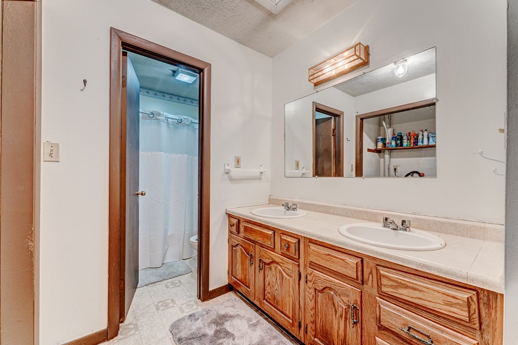 A bathroom with a wooden vanity and a mirror above it.