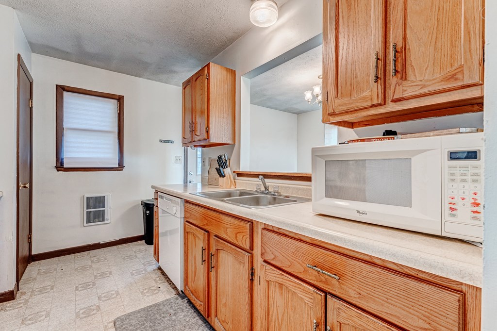 A kitchen with wooden cabinets and a white microwave.