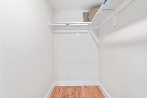 a room with white walls and a wood floor and a white shelf on the ceiling