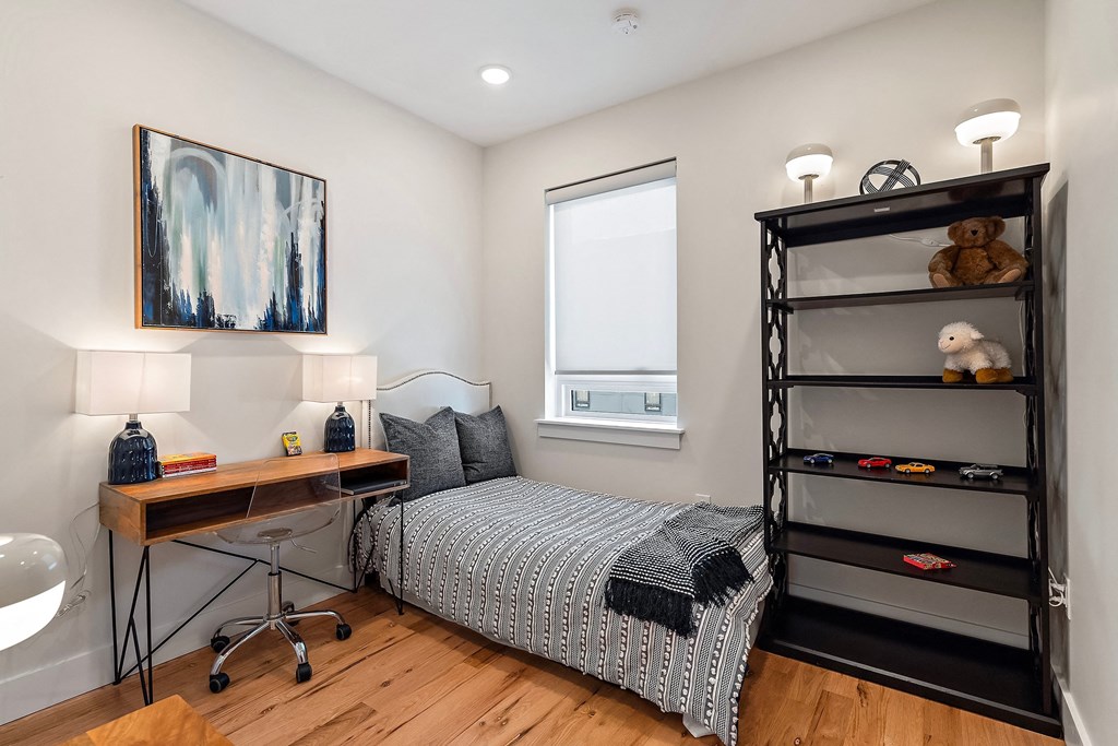 a bedroom with a bed and a desk with a shelf and a window