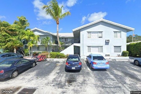 A white house with a blue car parked in front.