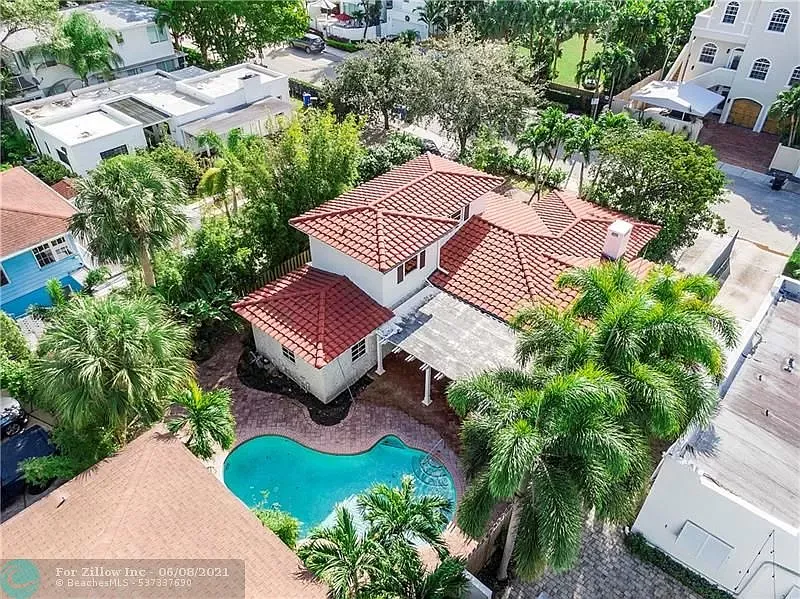 an aerial view of a house with a pool and palm trees