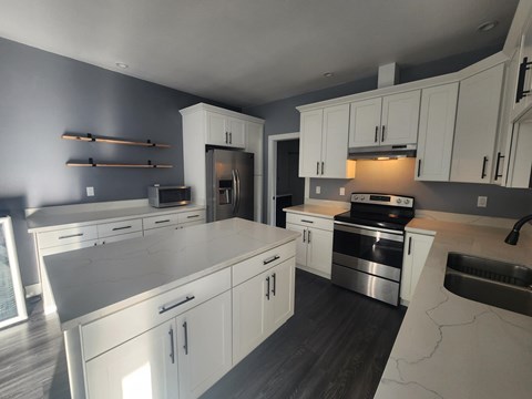 A modern kitchen with white cabinets and stainless steel appliances.
