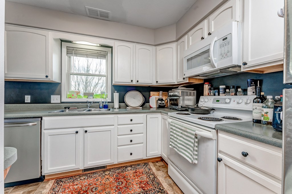 A kitchen with white cabinets and a stove top oven.