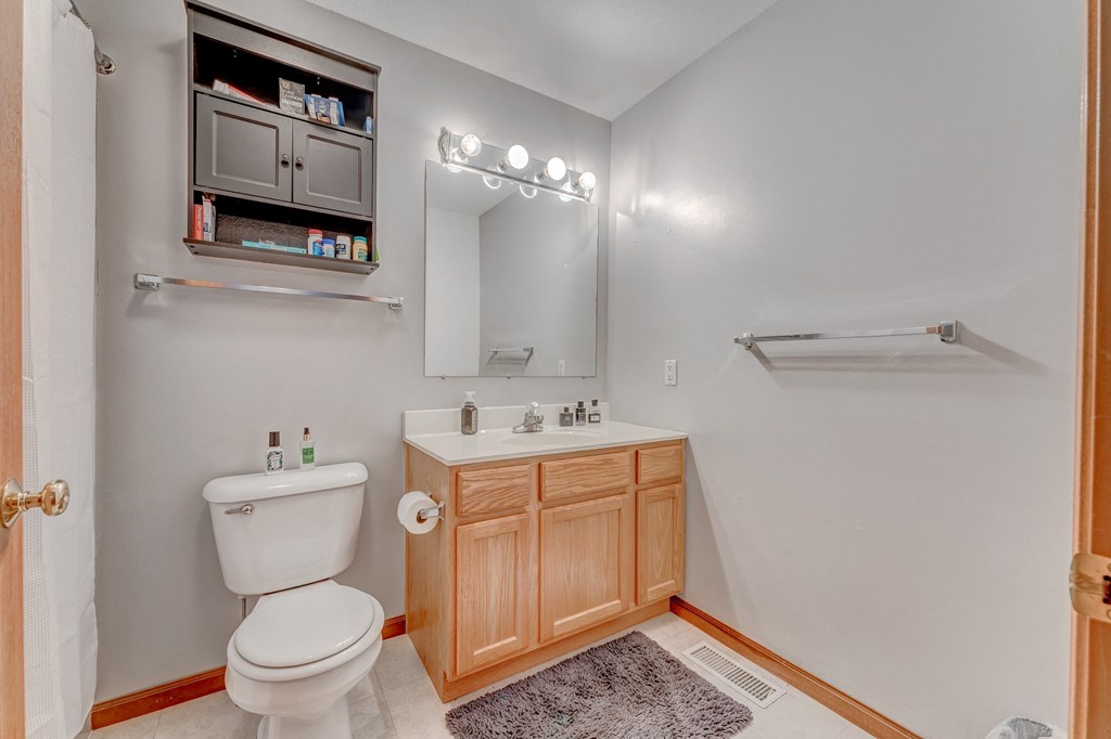 A white toilet sits in a bathroom with a wooden cabinet and medicine cabinet.