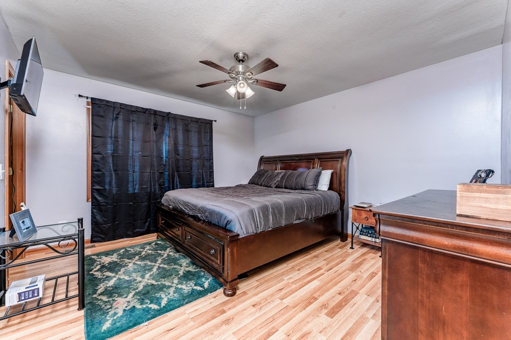 A bedroom with a bed, dresser, and ceiling fan.