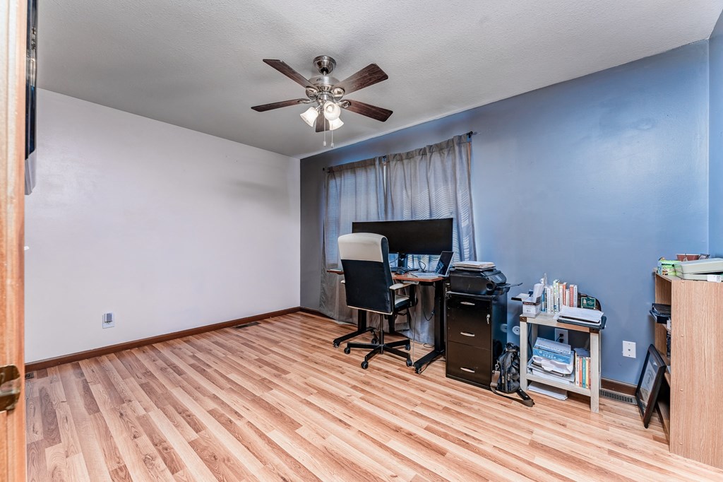 A room with a desk and a fan.