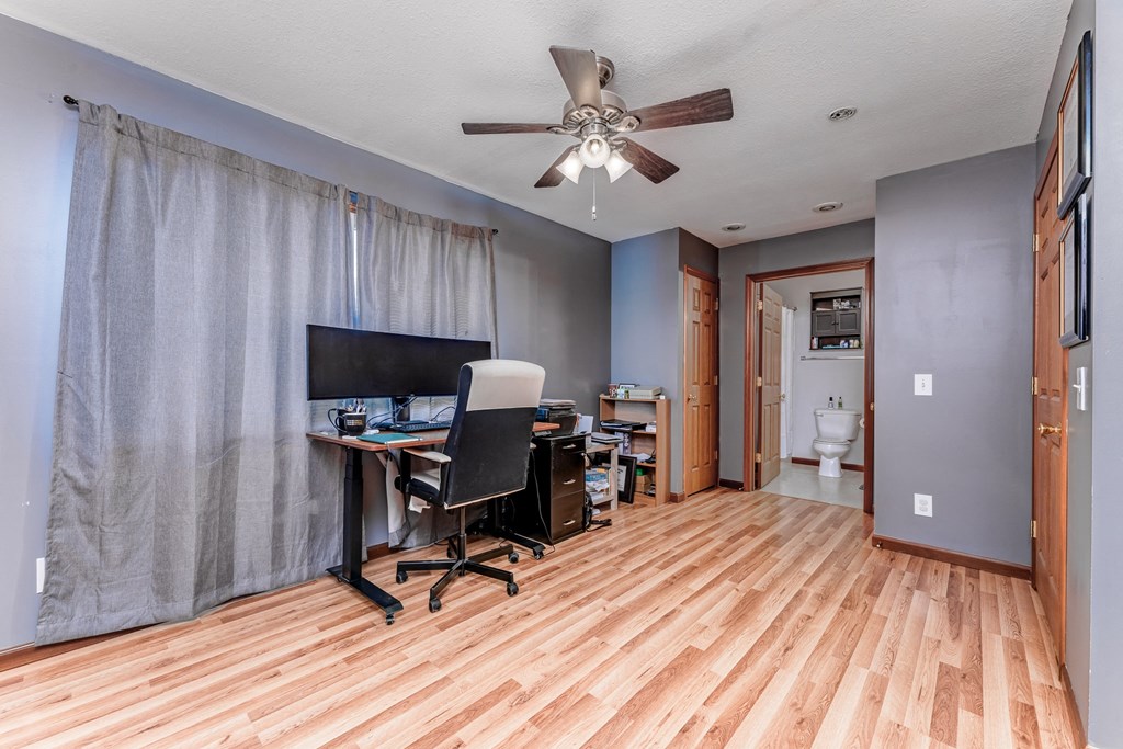 A room with a ceiling fan and a desk with a computer.
