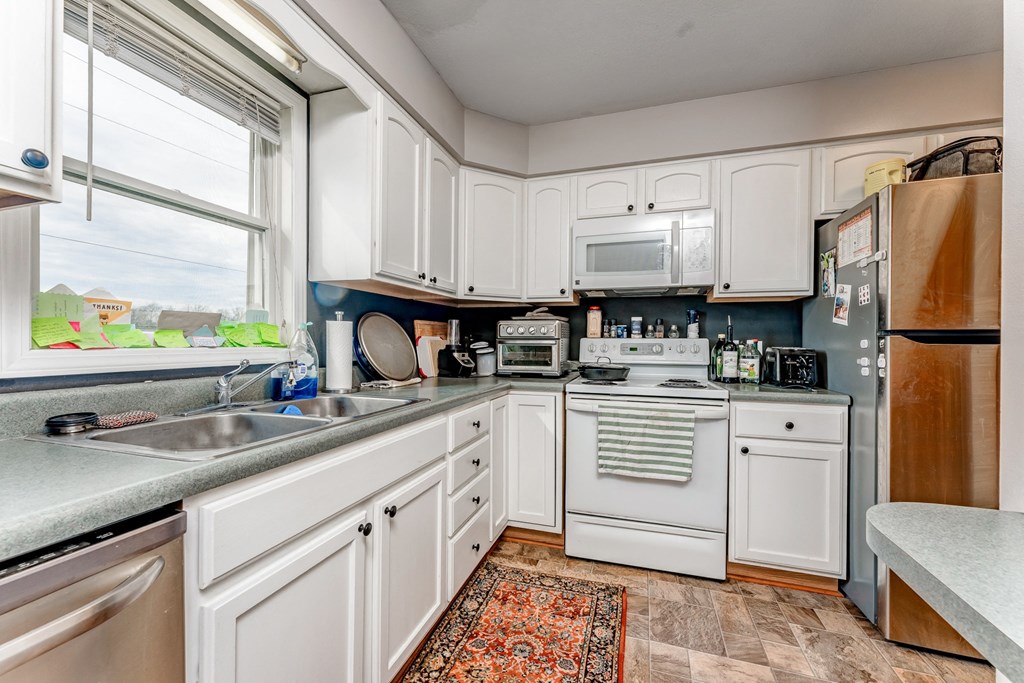 A kitchen with white cabinets and appliances.