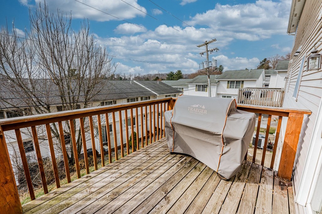 A Traeger grill is covered and sitting on a wooden deck.