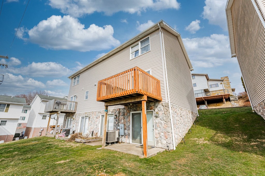 A house with a balcony and a door is in front of other houses.