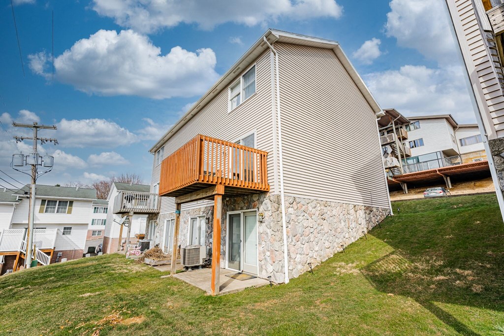 A house with a brown deck is surrounded by other houses.