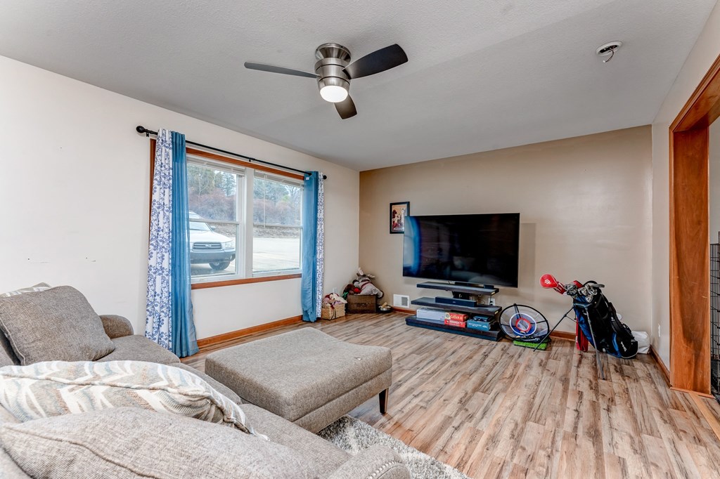 A living room with a grey couch, a television, and a ceiling fan.