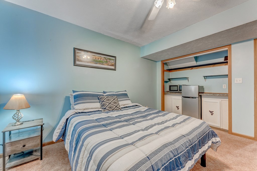 A bedroom with a bed, nightstand, and a painting on the wall.