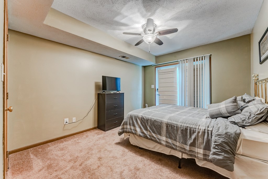 A bedroom with a bed, dresser, and window with curtains.