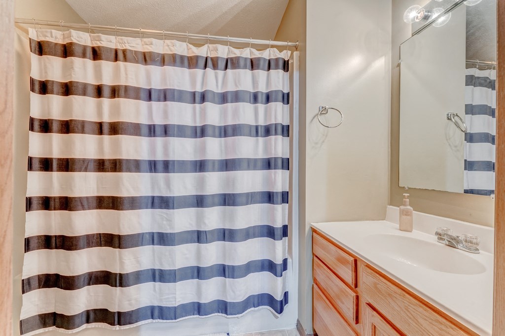 A bathroom with a striped shower curtain and a wooden vanity.