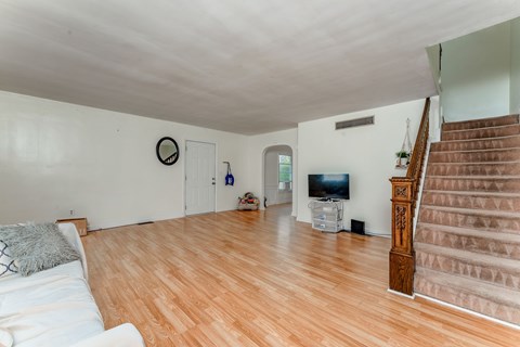 A living room with a white couch and a wooden staircase.