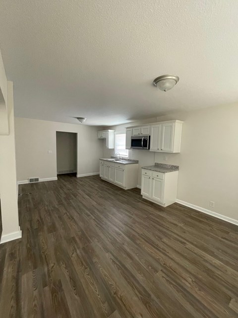 A kitchen with white cabinets and a microwave.