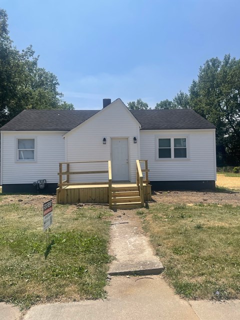 A small white house with a brown door and a wooden porch.