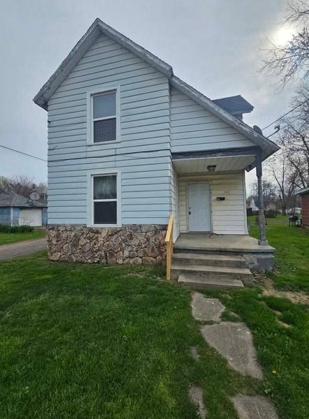 A small house with a stone wall in front.
