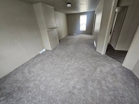 A long, empty hallway with carpeted floors and white walls.