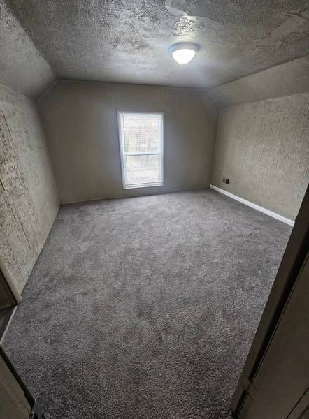 A room with a carpeted floor and a window letting in light.