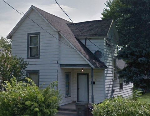 a white house with a brown roof on a street