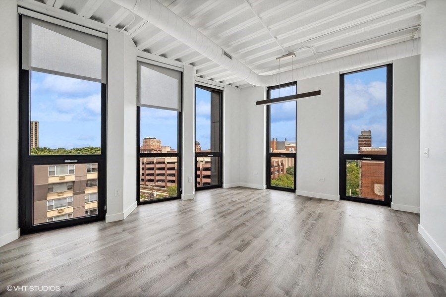an empty living room with large windows and a city view