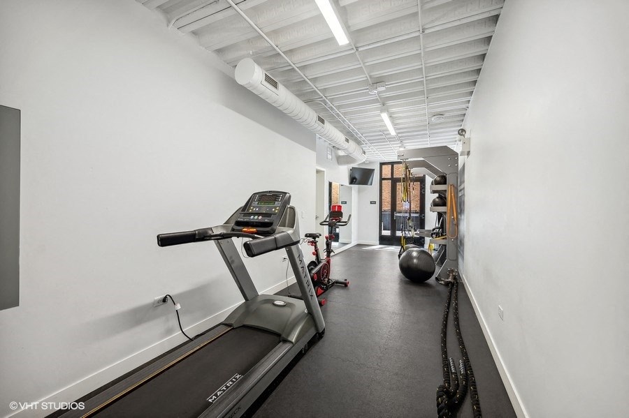 a gym with treadmills and weights in a room with white walls