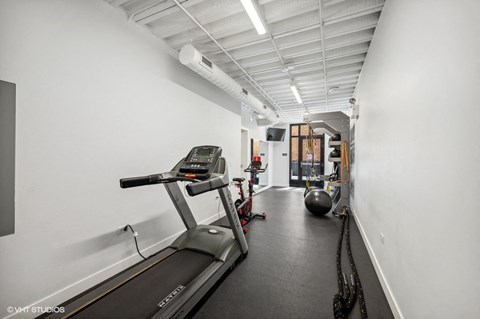 a gym with treadmills and weights in a room with white walls