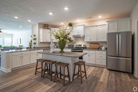 A kitchen with white cabinets and a wooden island.
