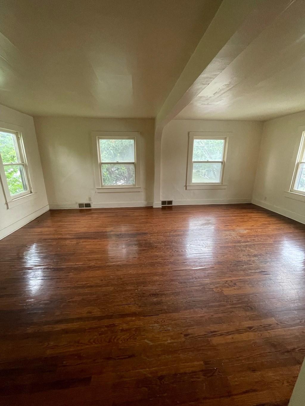 an empty room with wooden floors in a house