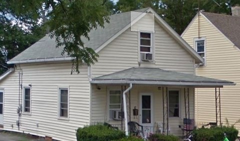 a white house with a gray roof and a tree