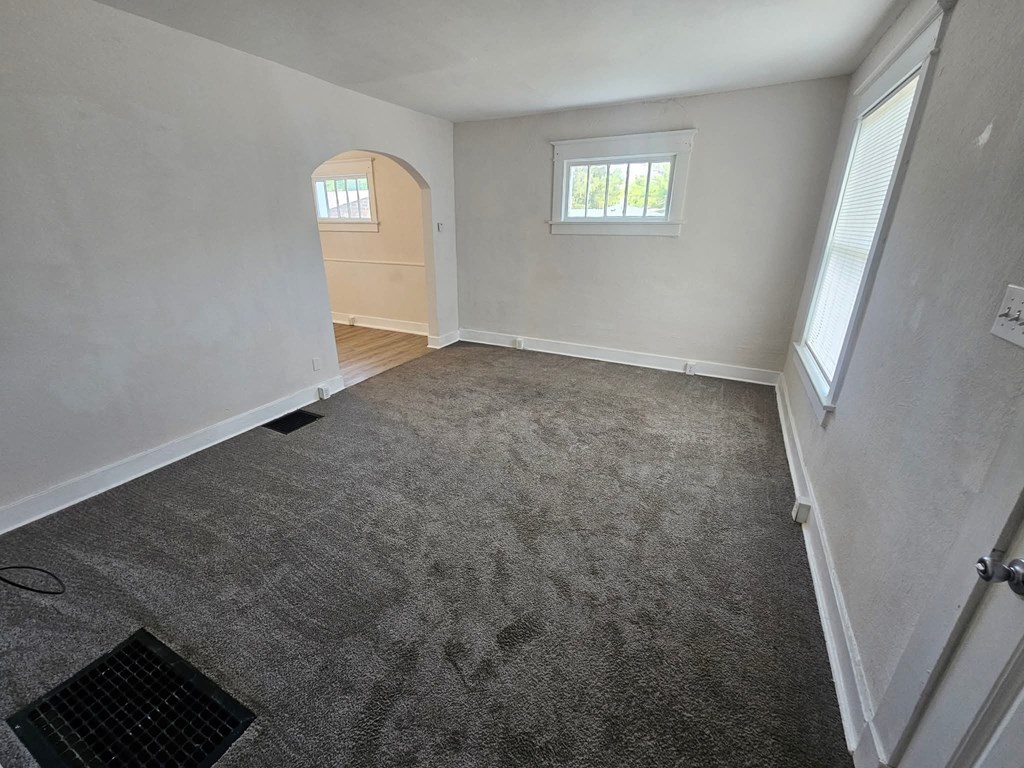 A room with a carpeted floor and a window with blinds.