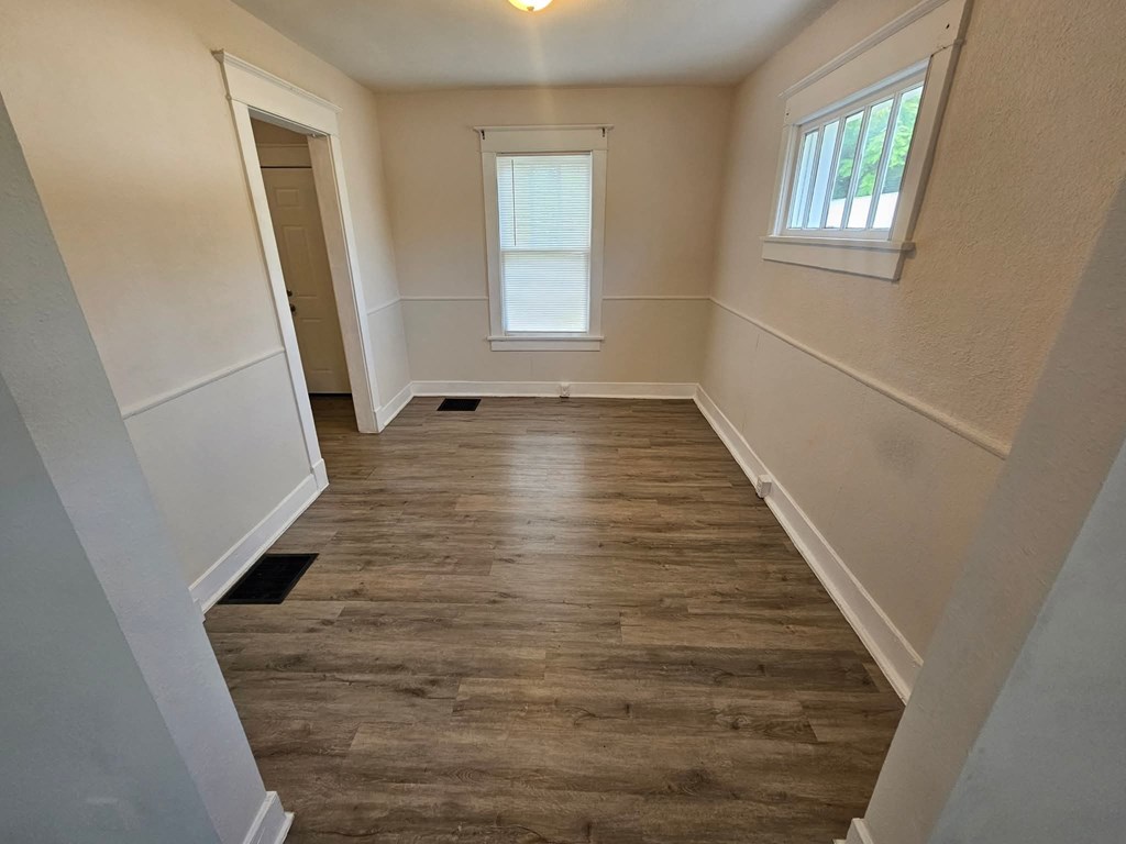 A room with wooden flooring and a window with blinds.