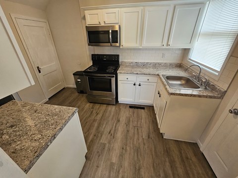 A kitchen with a granite countertop and wooden flooring.